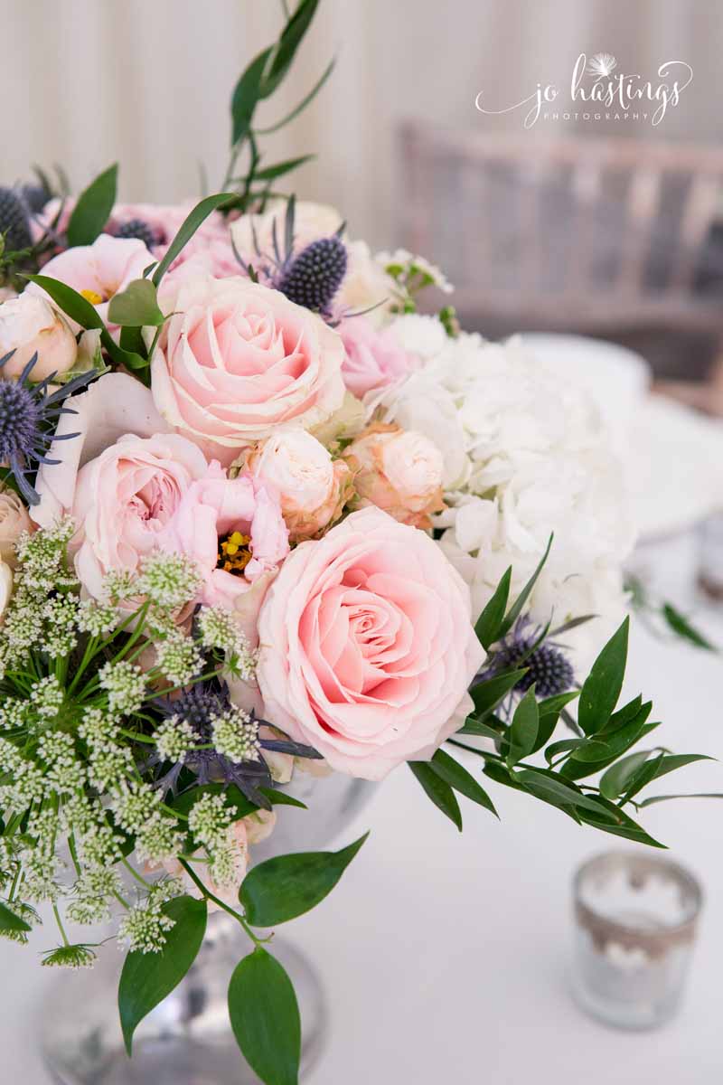 Blush pink roses and dusty blue thistles wedding centrepiece flowers low footed silver vases (1)