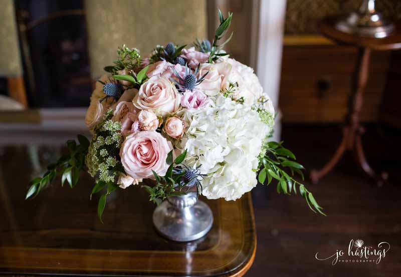 Dusty blue and pink flowers in silver footed bowl at wedding ceremony Heath House