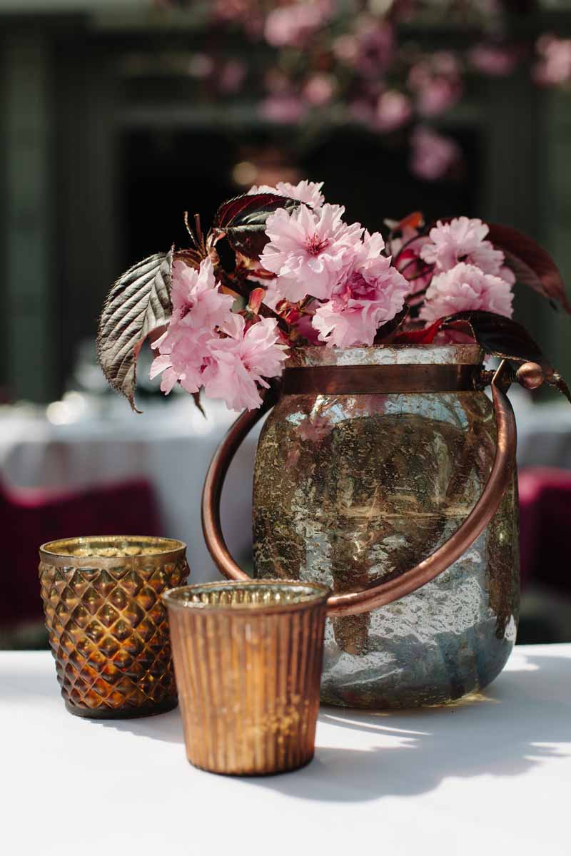 Bronze vases and votives with pink blossom perfect for a wedding centrepiece