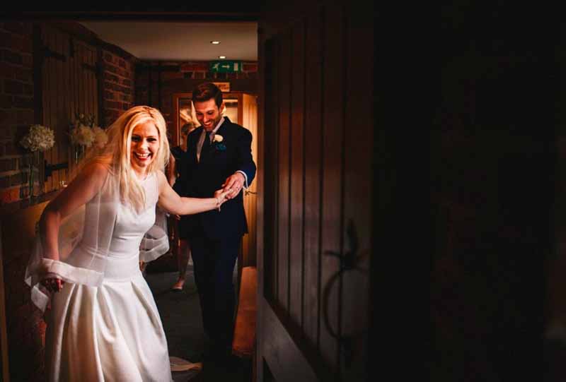 bride and grooom walking through curradine-barns-hydrangeas-to decorate the sideboards