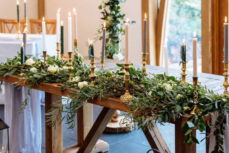 Wedding-ceremony-table-foliage-garlands-gold-candle-stick